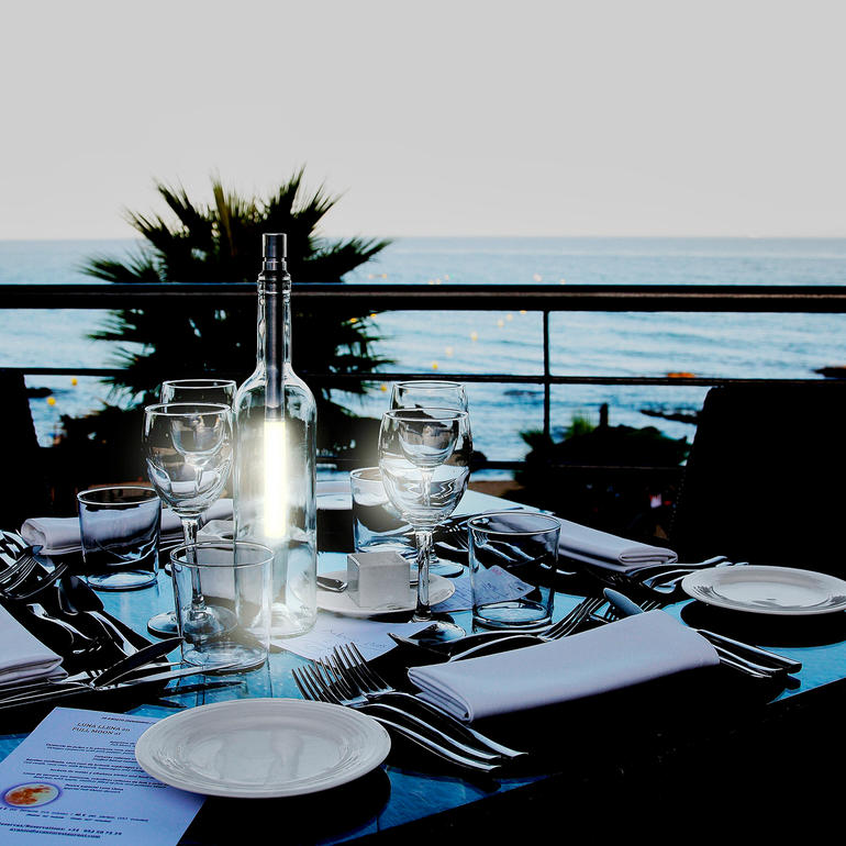 Glasflasche auf einem Tisch mit Blick auf das Meer.