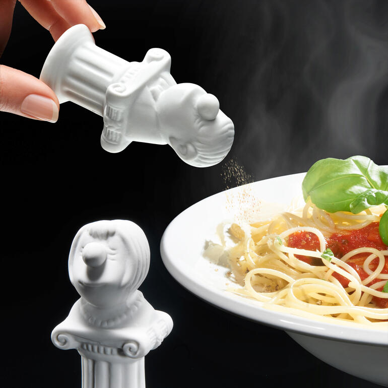 Salz- und Pfefferstreuer in Form einer Figur, über Pasta gestreut.