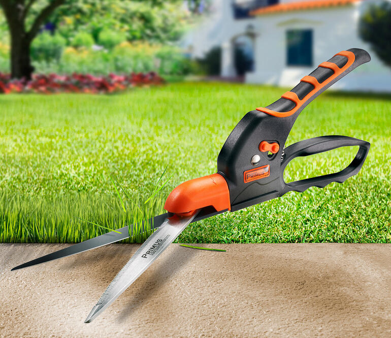 Zahnschneider mit orangefarbenem Griff schneidet Rasenrand.