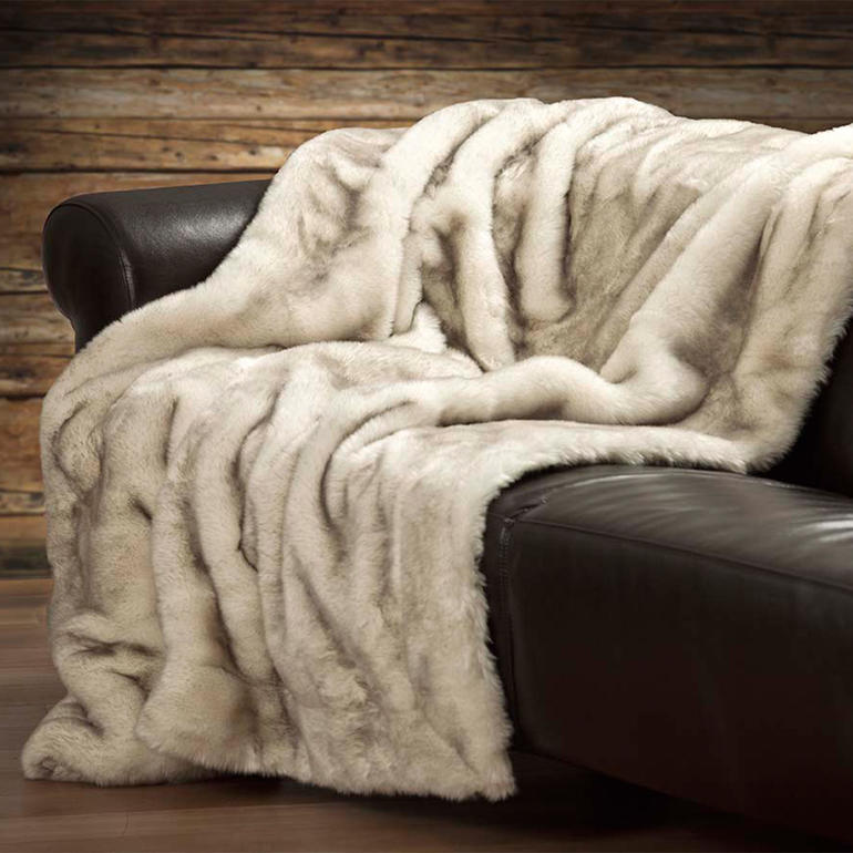 Polarfuchs-Webpelzdecke über einer Couch drapiert.