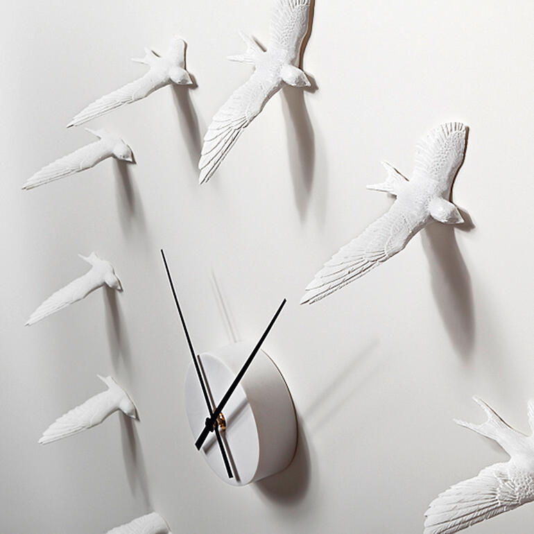 Durch die Skulpturen-Schatten wird der Eindruck lebendiger Schwalben noch verstärkt. Nahaufnahme der Schwalbenuhr, Detail der Flügel und Uhrwerk