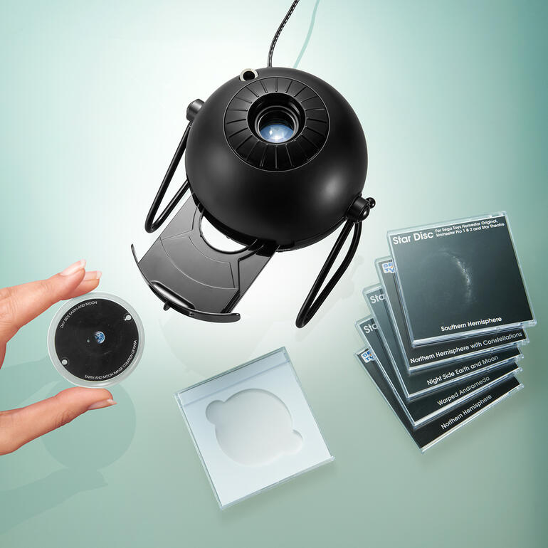 Heimplanetarium mit Projektionsdiscs und Hand nahe der Linse.