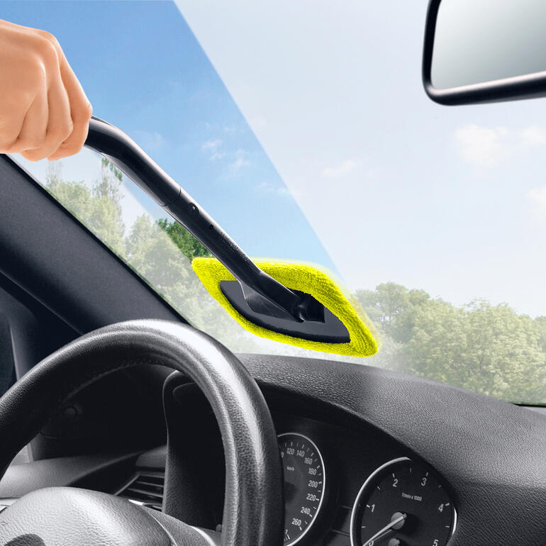 Person reinigt Autoscheibe mit einem Handgriff und gelber Reinigungspads.