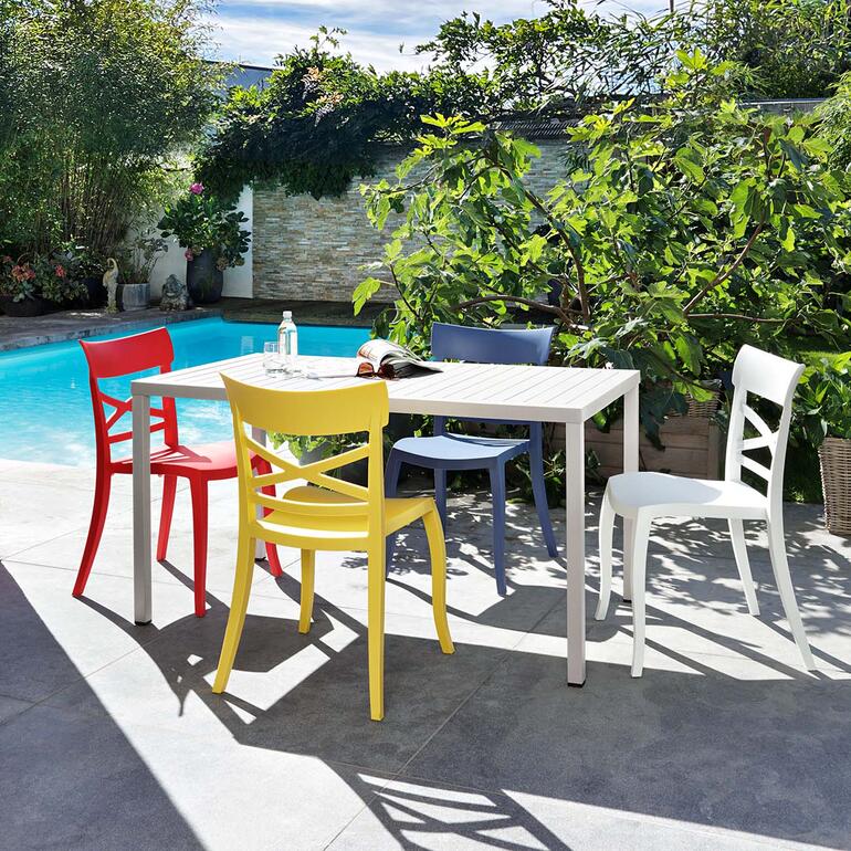 Wohnlicher als die üblichen, oft langweiligen Draussen-Stühle. Bunte Design-Stühle im Freien um einen Tisch herum.