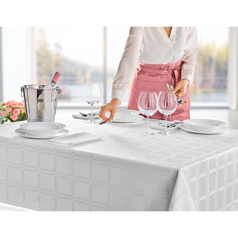 Tischdecke, Weiss Frau deckt einen Tisch mit einer fleckabweisenden Tischdecke und Gläsern.