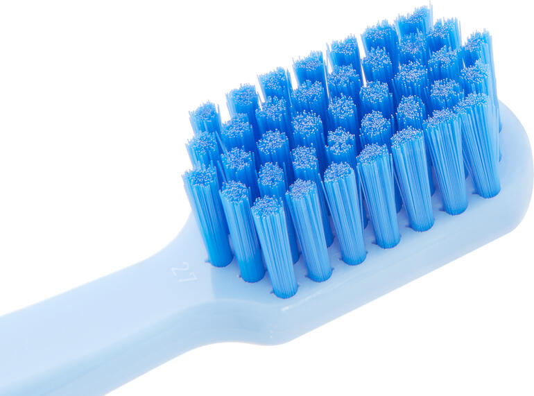 Nahaufnahme eines weißen Zahnbürstenkopfes mit blauen Borsten.