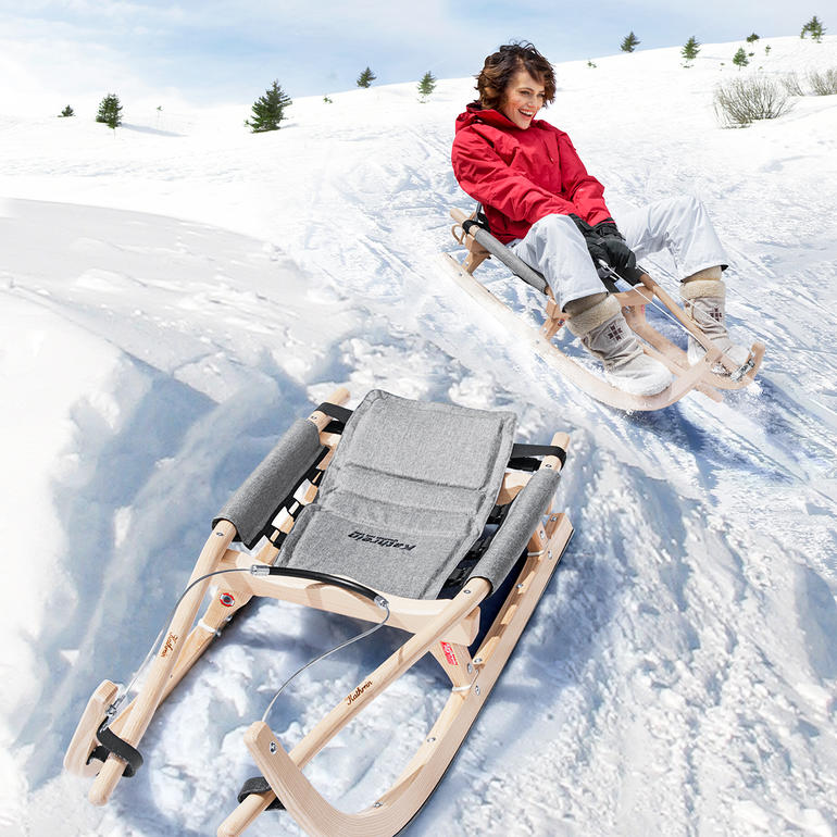 Kind fährt mit einer Holzschlitten im Schnee.