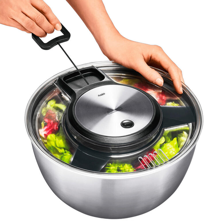 Person mit Hand betätigt eine Salatschleuder.