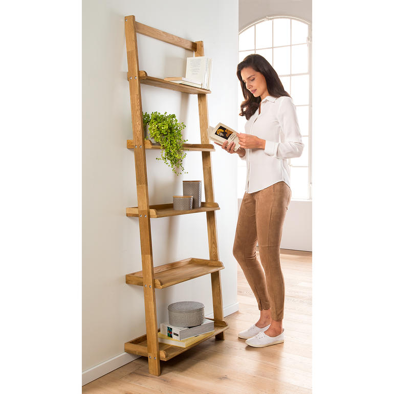 Frau liest ein Buch an einem Eiche-Leiterregal.