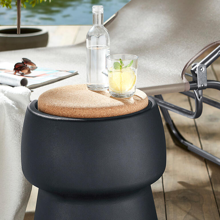 Champ Hocker mit Korkdeckel neben Getränken auf einer Terrasse.
