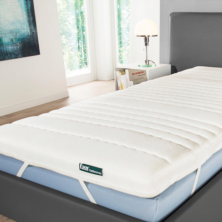 Federkern-Matratzenauflage auf einem Bett in einem modernen Schlafzimmer.