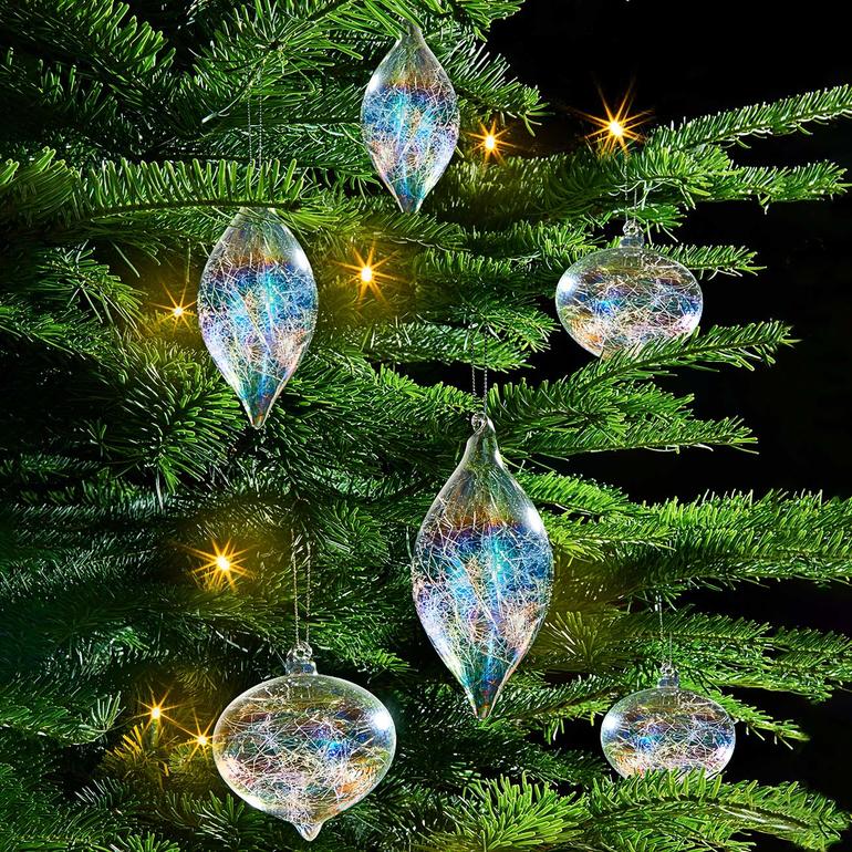 Sechs iriserende Glasfäden baumeln als Christbaumschmuck.