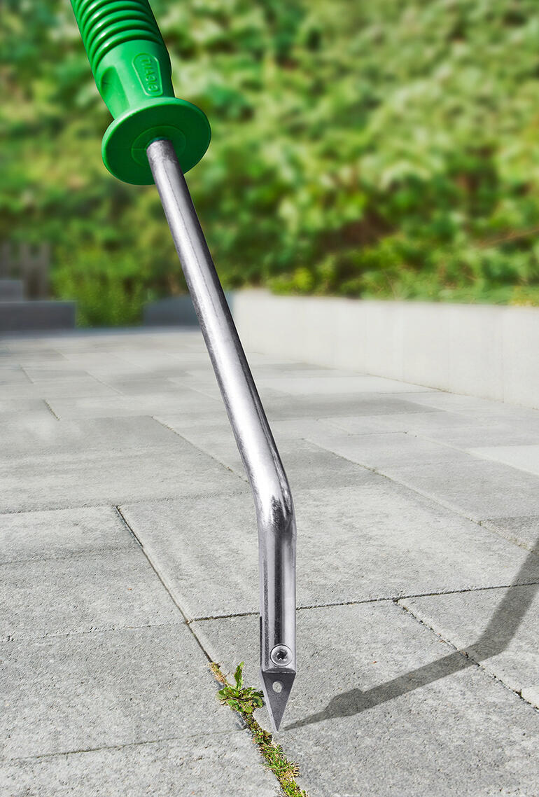 Fugenkratzer mit V-Schneide auf einem gepflasterten Weg.