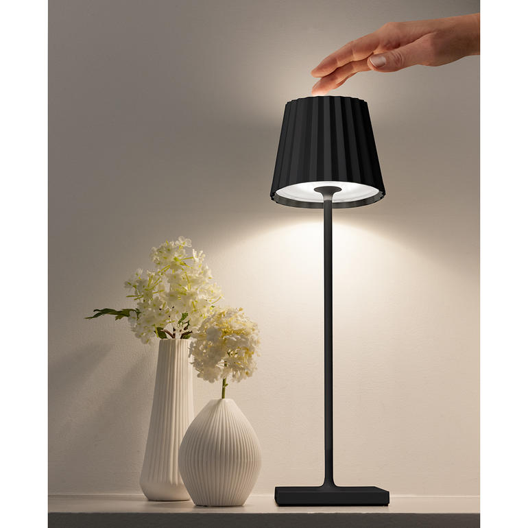 Il suffit d’appuyer avec votre doigt sur la tête de la lampe pour ajuster l’intensité lumineuse à vos besoins. Design Akku-Tischleuchte mit schwarzem Schirm und quadratischem Sockel.