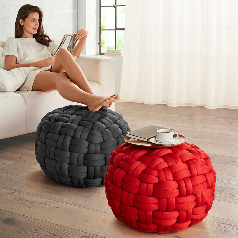 Zwei bunte, geflochtene Poufs in Grau und Rot im Wohnbereich.