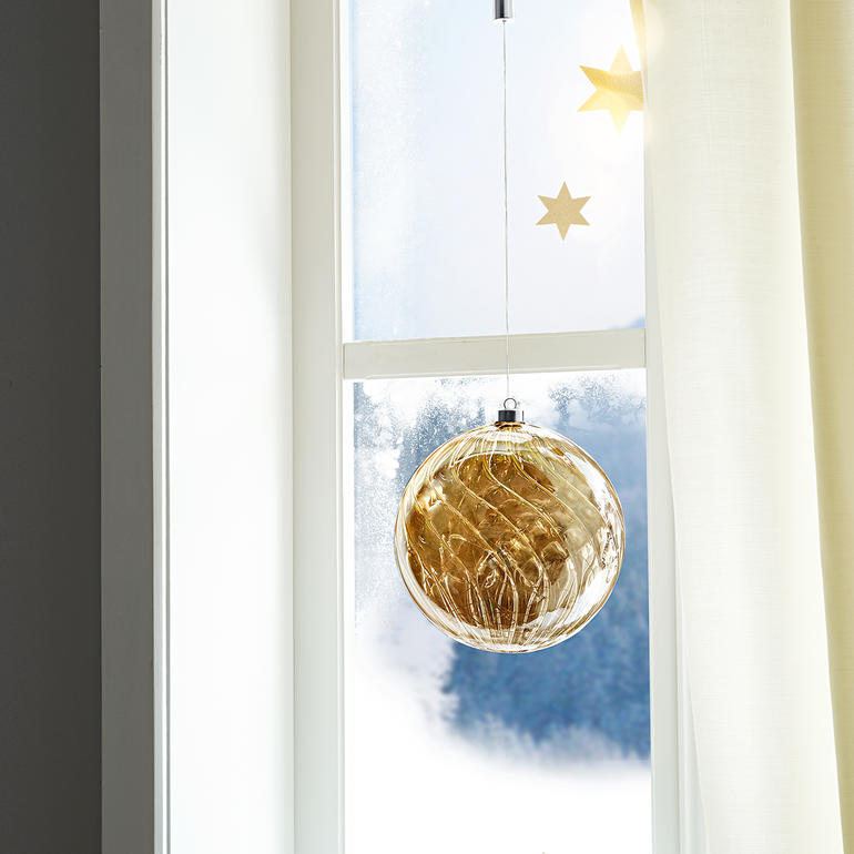 Une belle décoration à suspendre ou à poser. En journée, le verre se pare de reflets mystérieux, telle de l’ambre. Getönte Glaskugel mit Mikro-LEDs hängt am Fenster