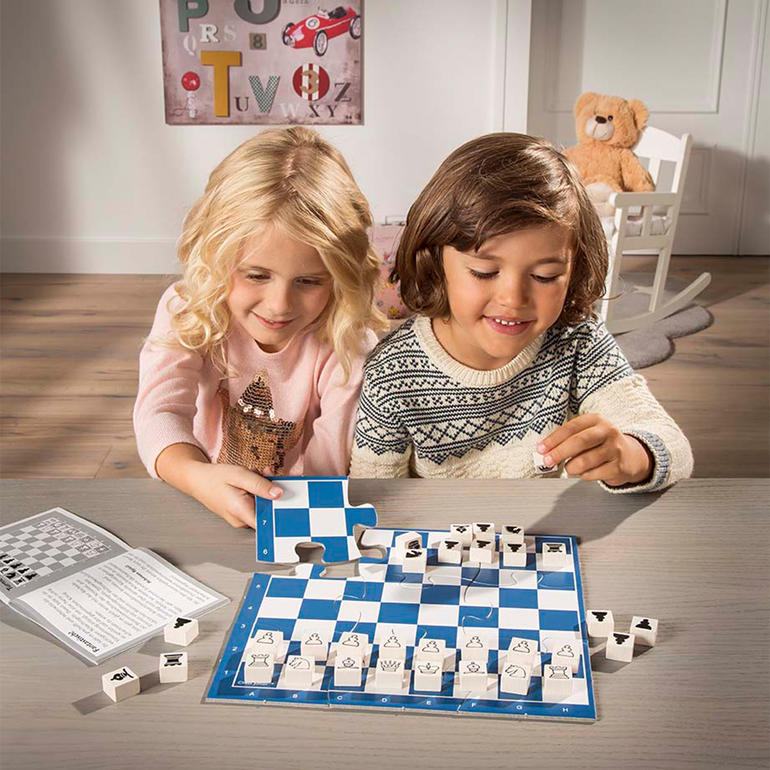 Kinder spielen Schach mit dem Spiel Chess Junior auf einem Tisch.