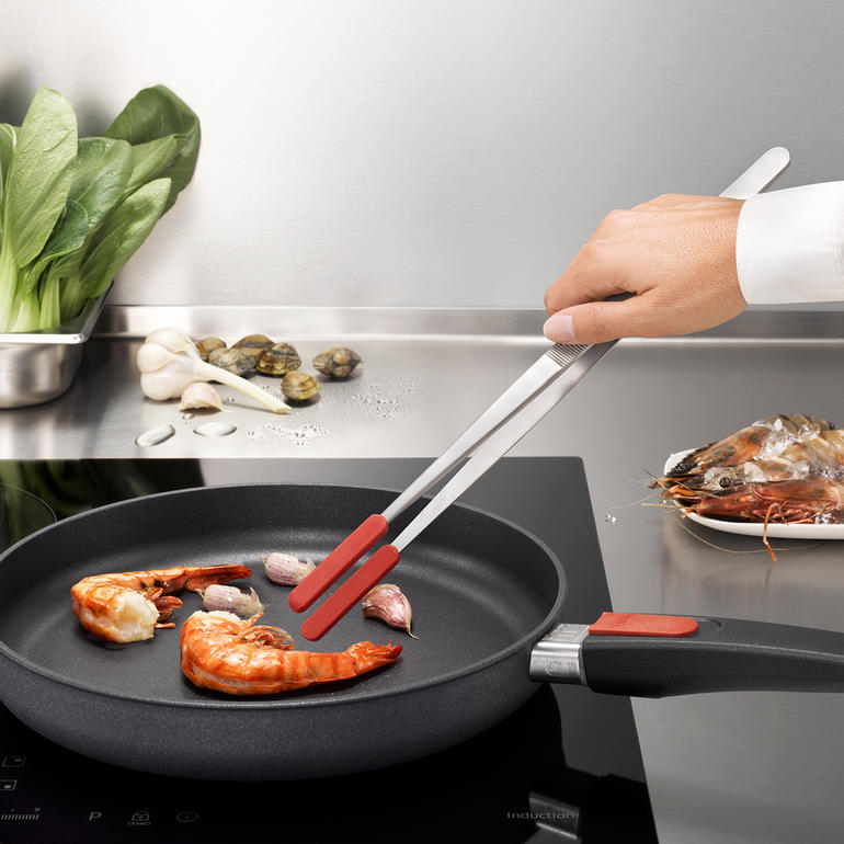 Küchenpinzette mit roten Silikonspitzen bei der Zubereitung