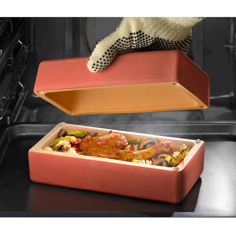 RÖMERTOPF® BBQ Brick mit Hähnchenkeule und Gemüse im Innenraum, Deckel wird angehoben.