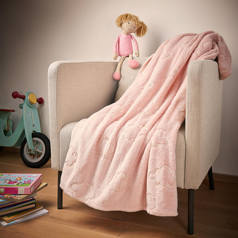 Bei Tageslicht sieht man der Kuscheldecke ihr leuchtendes Geheimnis noch nicht an ... Leuchtende Kuscheldecke in Rosa mit Wolken auf einem Sessel
