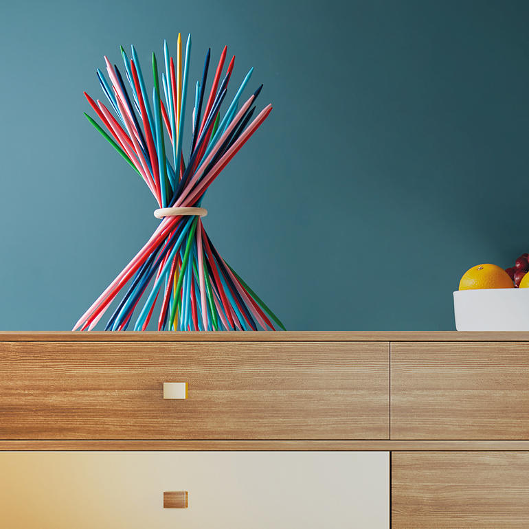 Farbenfrohe XXL-Sticks in einer künstlerischen Anordnung auf einem Holztisch.