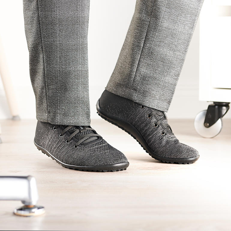 Mann trägt schwarze Barfuß-leguano® Knit-Sneaker in einem modernen Büro.