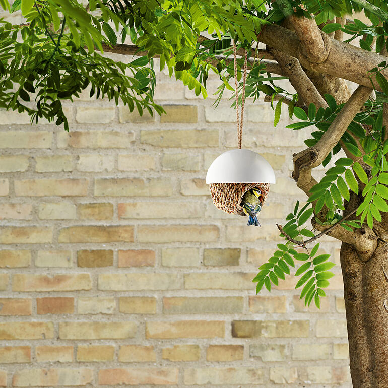 Vogelnest aus weichem Material hängt an einem Baum.