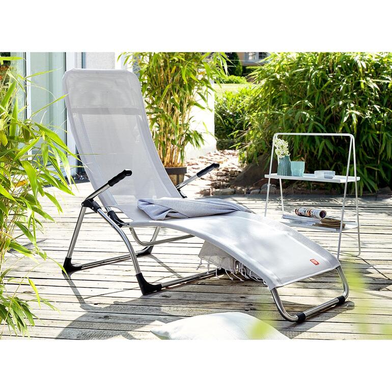 Klappbare Sitzliege steht auf einer Terrasse, umgeben von Pflanzen.