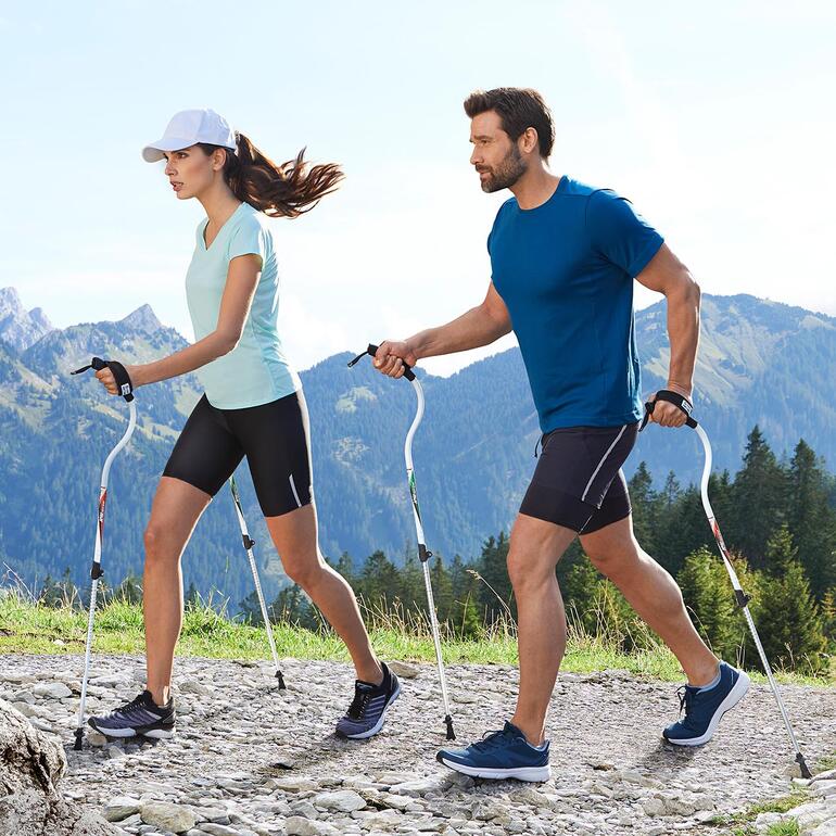 Mann und Frau gehen mit Ergocurve Walkingstöcken in der Natur.
