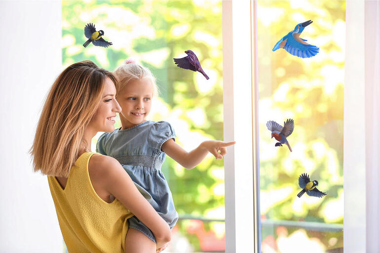 Mutter mit Kind vor einem Fenster mit Vogelaufklebern