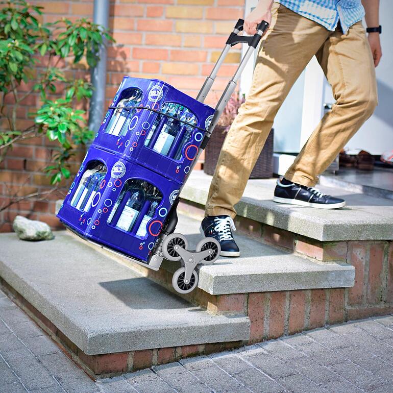 Mann mit Faltbarer Treppen-Sackkarre, die zwei Getränkekisten transportiert