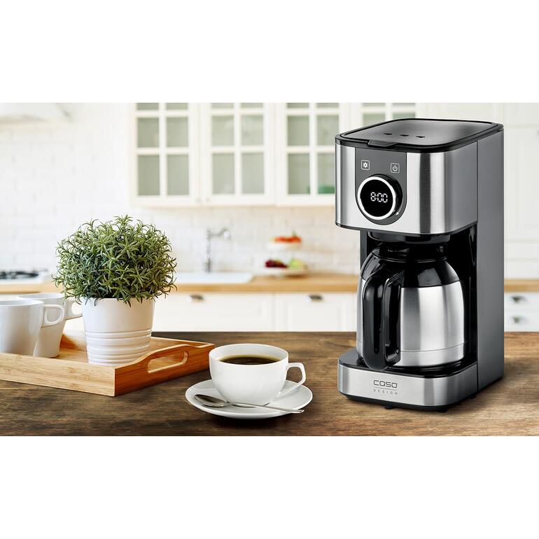 Design-Kaffeemaschine mit Edelstahlkanne auf Tisch.