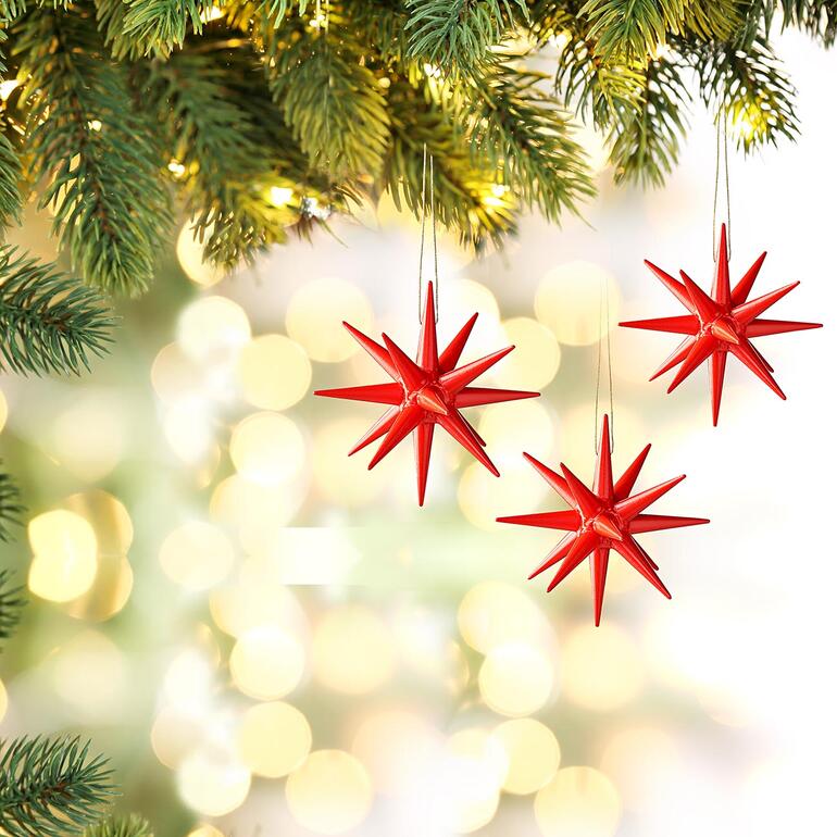 Rouge Drei rote Seiffener Weihnachtssterne hängen an einem dekorierten Weihnachtsbaum.