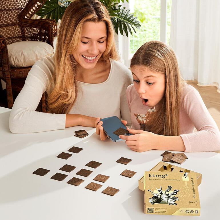 Frau und Mädchen spielen mit Klang-Memo Karten auf einem Tisch