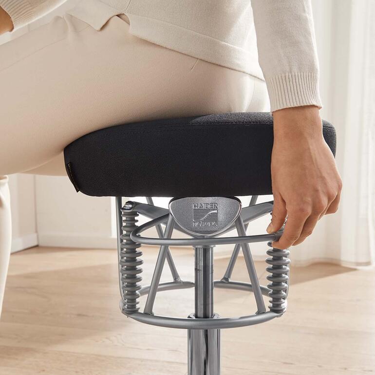 Detailaufnahme der Hand einer Frau, die am ergonomischen Stuhl einen Regler einstellt.