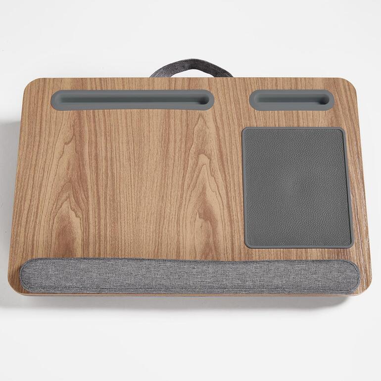 Mit gepolsterter Handgelenkauflage, 2 Standrillen zum kippfesten Halten Ihrer Mobilgeräte sowie fest integriertem Mousepad. Holzablage für Laptop mit grauer Stoffauflage.