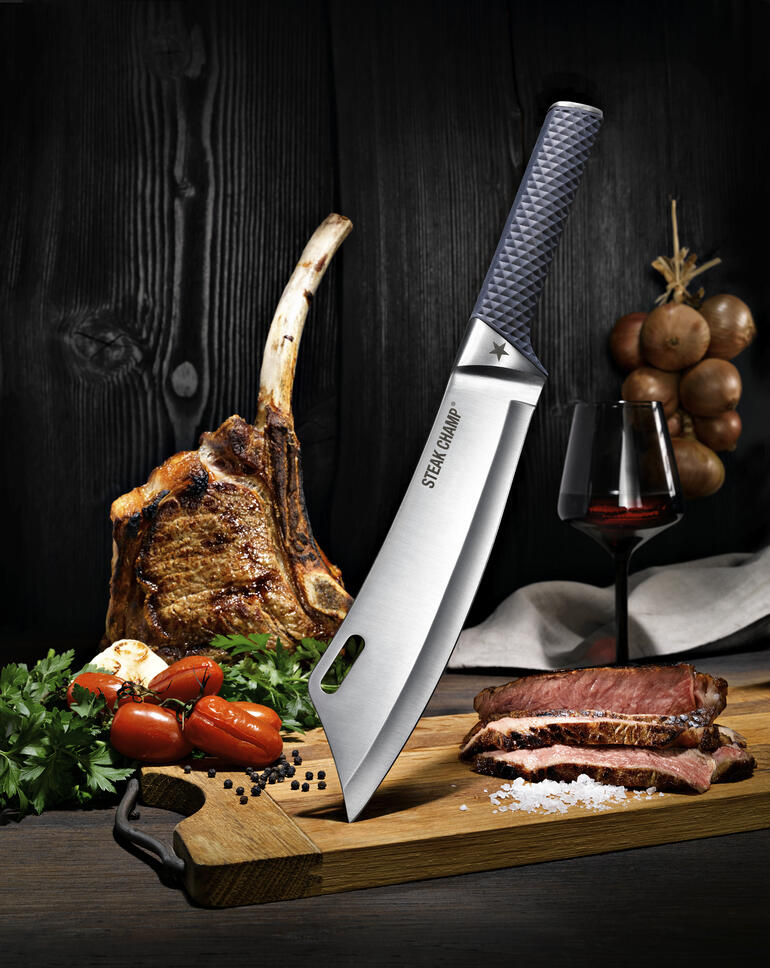 SteakChamp Kochmesser BBQ Pro SteakChamp Kochmesser auf einem Holzbrett, neben einem Stück Fleisch und einer Weinflasche.