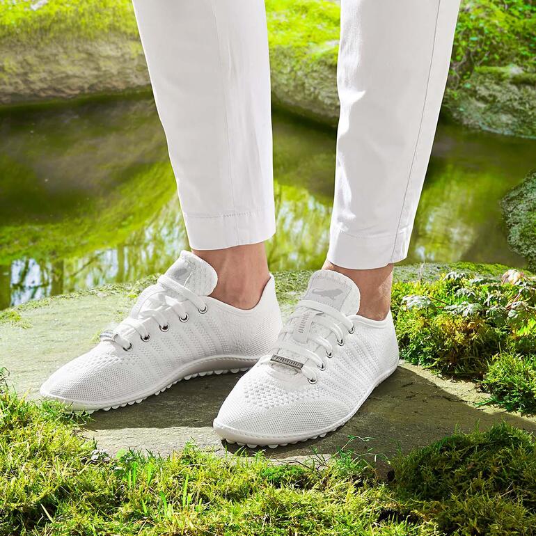 Barfuß-leguano Sneaker in Weiß, getragen von einer Person.