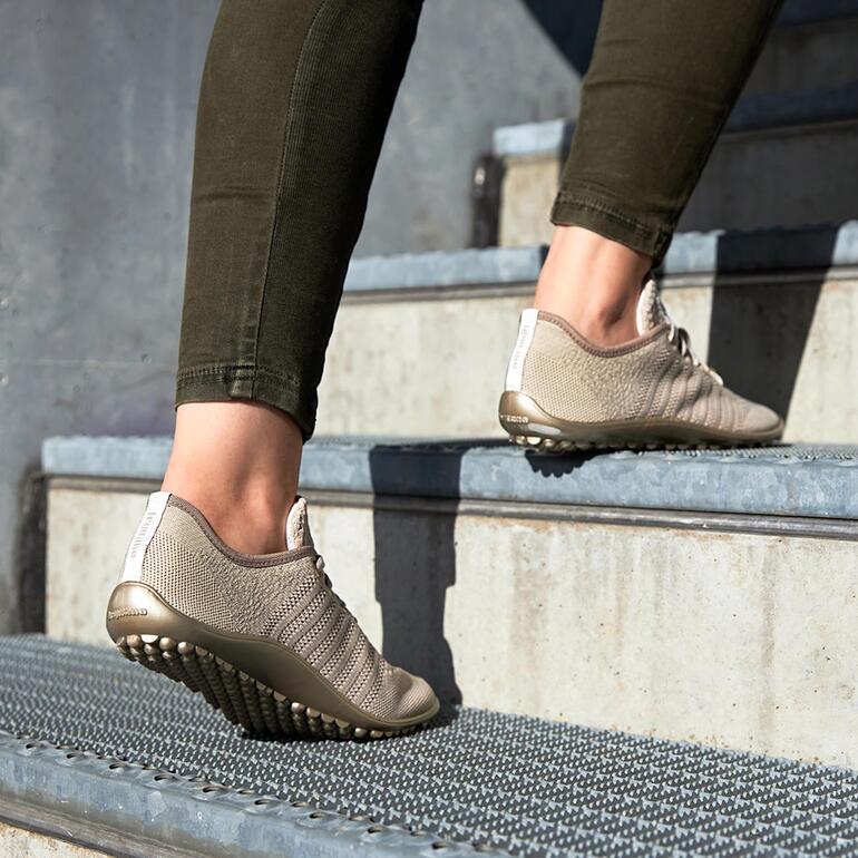 Barfuß-leguano Sneaker in Beige, getragen auf einer Treppe.