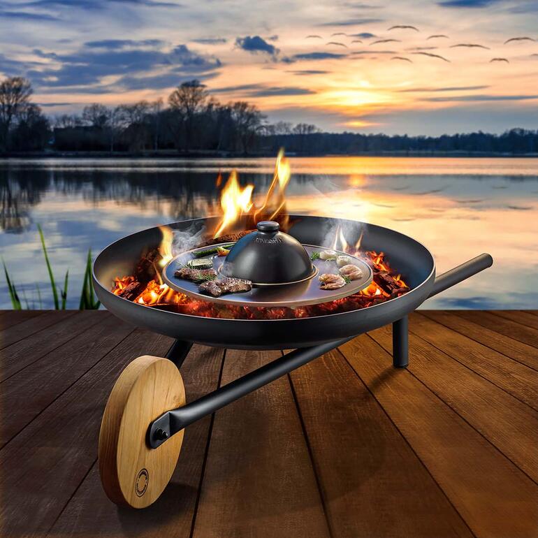 RÖMERTOPF BBQ Planet auf einer Holzterrasse, umgeben von Wasser und Bäumen.