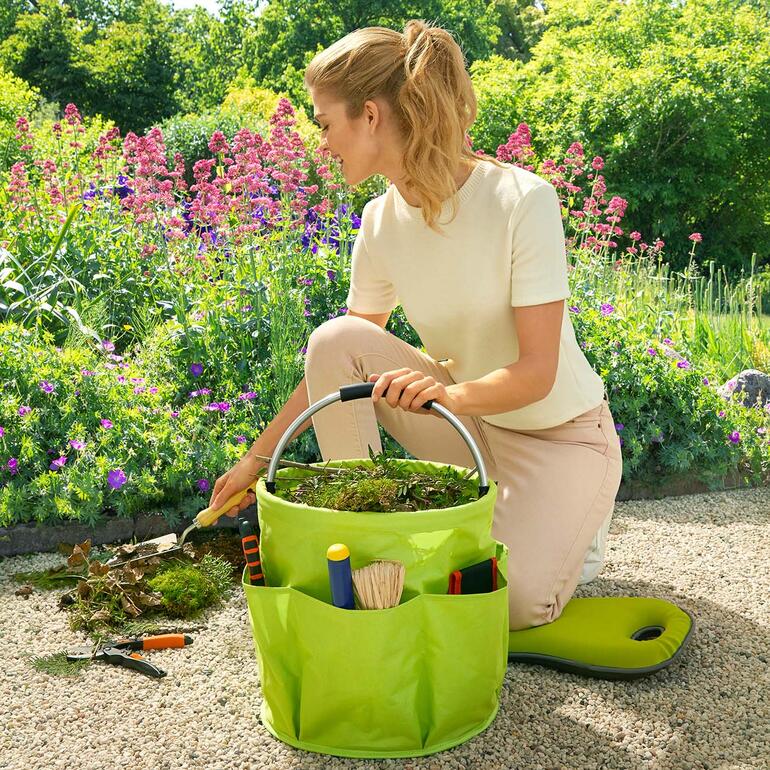 Frau pflanzt mit einem Garten Caddy in einem bunten Garten.
