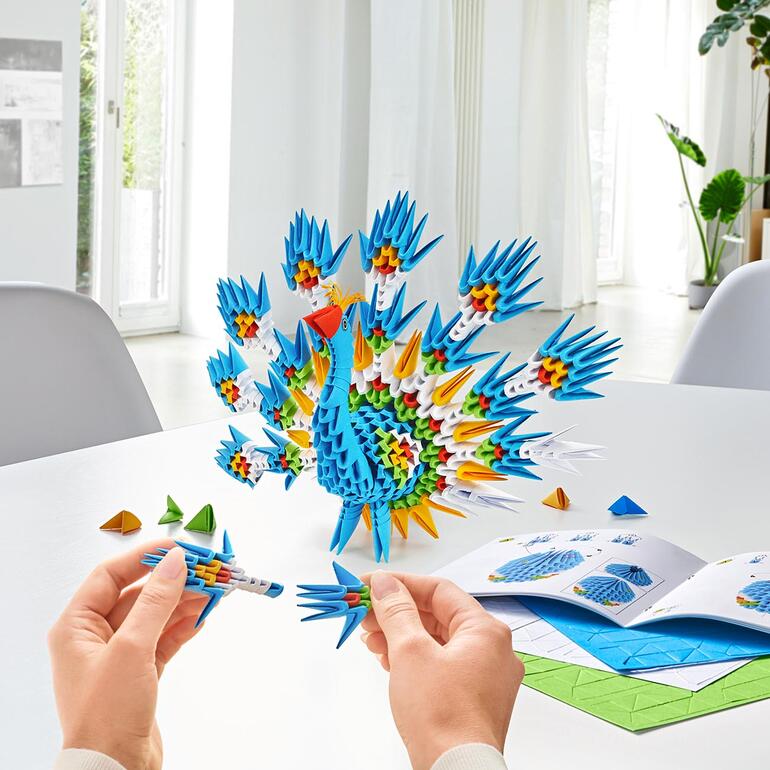 Bunt gefalteter 3D Origami Pfau auf einem Tisch, erstellt aus Papier.