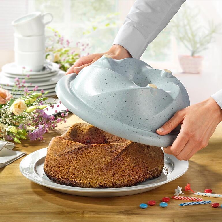 Koch zeigt den CeraFlam Gugelhupfbäcker mit frisch gebackenem Kuchen.