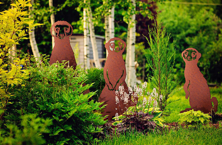Erdmännchen-Gartenstecker Set in einem Garten mit verschiedenen Pflanzen.