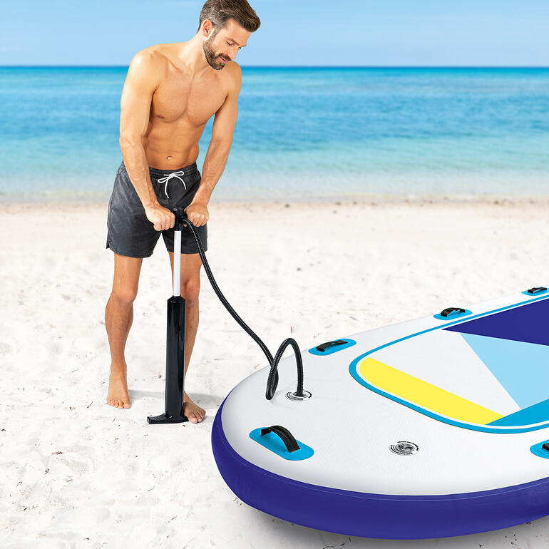 In ca. 15 Minuten aufgeblasen und fahrbereit. Mann pumpt aufblasbares SUP-Board am Strand auf.