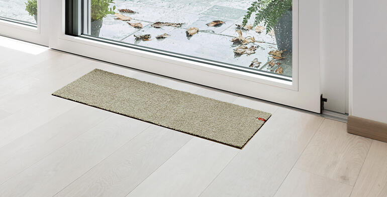 Terrassentür Fußmatte in beige vor einer Glastür.