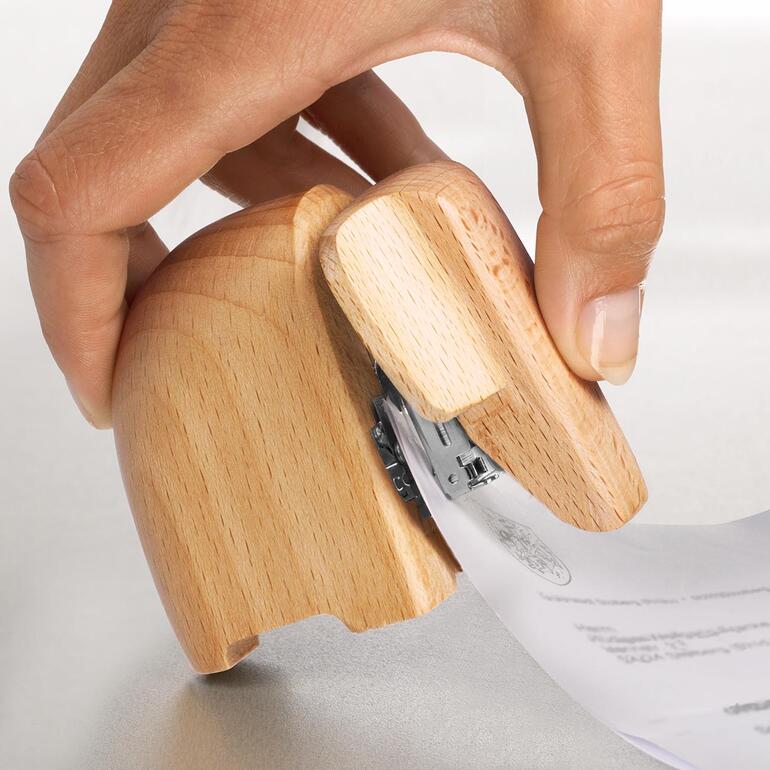 Hefter Elefant Hand hält Papiere, während sie einen Holz-Elefanten-Heftgerät benutzt.