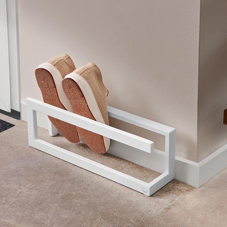 Schuhregal mit einem Paar beigen Sneakers, die auf einer weißen Ablage stehen.