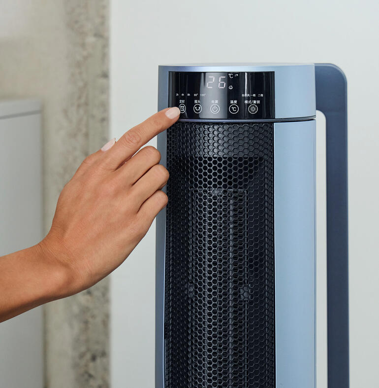 Hand am Bedienfeld des PTC Keramik-Heizlüfters mit Temperaturanzeige