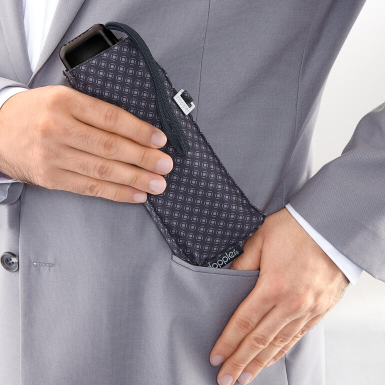 Hände stecken einen Carbonstahl-Taschenschirm in die Anzugtasche.